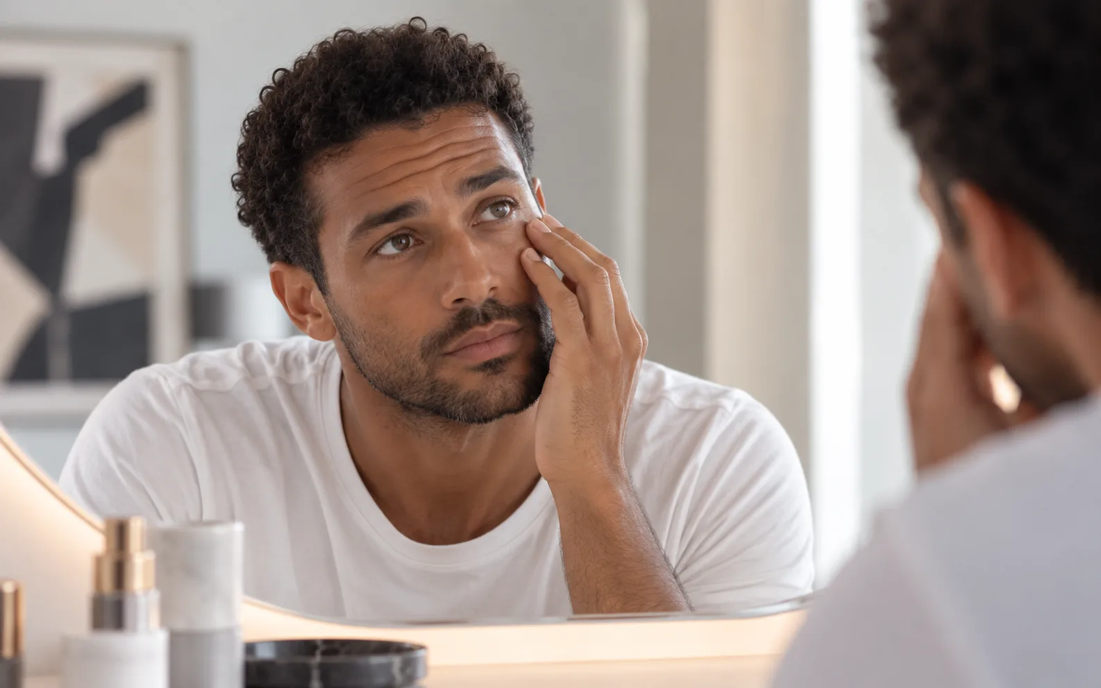 Homme examinant la zone sous son œil devant un miroir